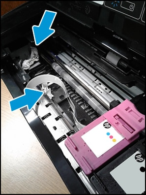 View inside a printer showing crumpled paper in the carriage path causing a carriage jam